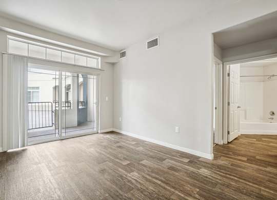 Model Living Room with Wood-Style Flooring and Patio Accessibility at Altitude on Fifth Apartments located in Salt Lake City, UT.