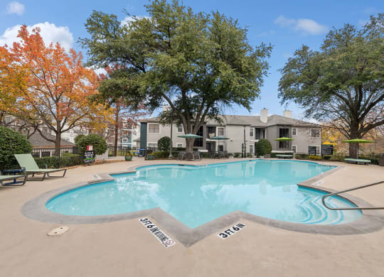 Community Swimming Pool with Pool Furniture at Bridges at Oakbend Apartments in Lewisville, TX.