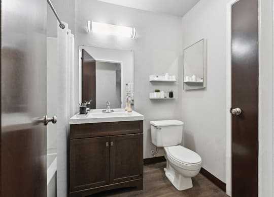 Model Bathroom with Dark Wood Cabinets and Wood-Style Flooring at Creek at 2645 Apartments located in Sacramento, CA.