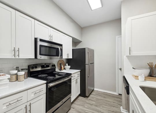 Model Kitchen with Wood-Style Flooring and White Cabinets at Allure North Dallas Apartments located in Dallas, TX.