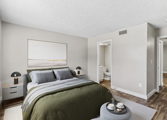 Model Bedroom with Wood-Style Flooring and Attached Bathroom at Meadow Ridge Apartments in Las Vegas, NV.