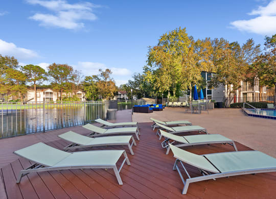 Outdoor Pool Deck Area with Pool Furniture at Vue at Baymeadows Apartments in Jacksonville, FL.
