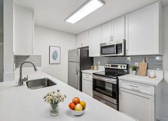 A modern kitchen with white cabinets and appliances.