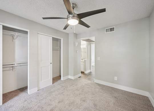 Model living room with a ceiling fan and carpeted floor.