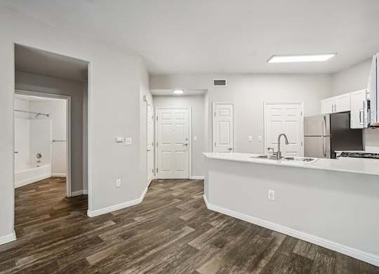 Model Kitchen with Wood-Style Flooring, White Cabinets, and Stainless-Steel Appliances at Altitude on Fifth Apartments located in Salt Lake City, UT.