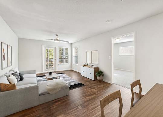 Model Living Room with Wood-Style Flooring and Patio Accessibility at Lake Cameron Apartments located in Apex, NC.