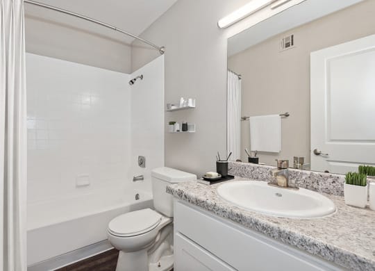Model Bathroom with White Cabinets, Wood-Style Flooring and Shower/Tub at Peaks on 4th Apartments in Avondale, AZ.