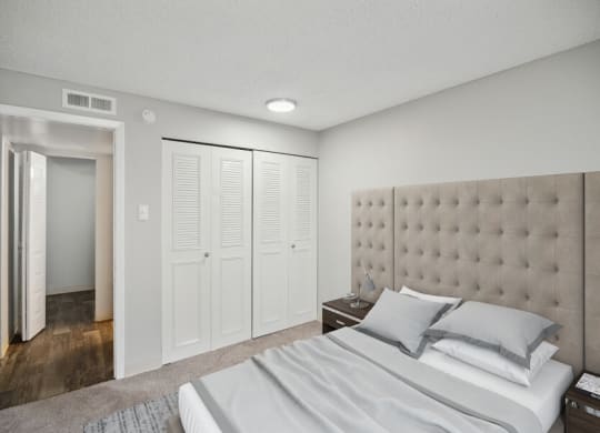 a bedroom with white walls and a white bed with gray pillows