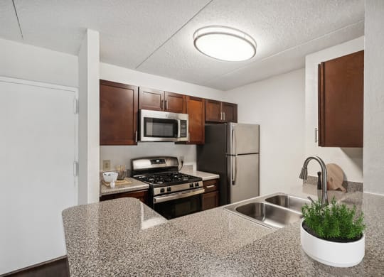 Model Kitchen with Dark Wood Cabinets & Wood-Style Flooring at Mason Van Dorn Apartments located in Alexandria, VA.