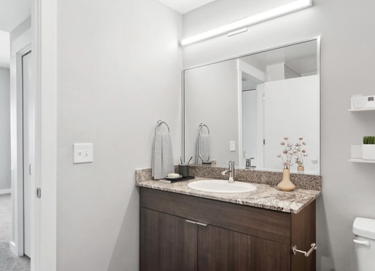 Model Bathroom with Wood-Style Flooring and Dark Oak Cabinets at Seven Skies Apartments located in Sandy, UT.