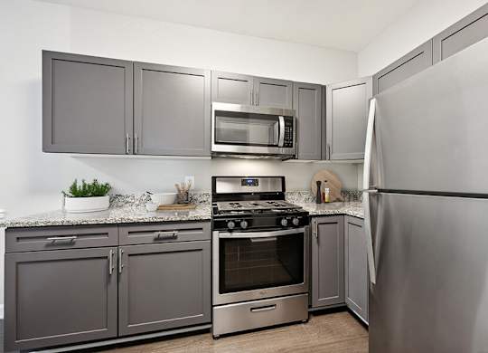 Model Kitchen with Dark Wood Cabinets and Wood-Style Flooring at Dulles Green Apartments located in Herndon, VA.