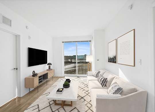 Model Living Room with Wood-Style Flooring and Patio Accessibility at Stella Apartments located in New Carrollton, MD.