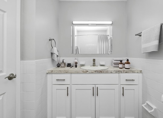 Model Bathroom with White Cabinets and Wood-Style Flooring at Stone Ends Apartments in Stoughton, MA.