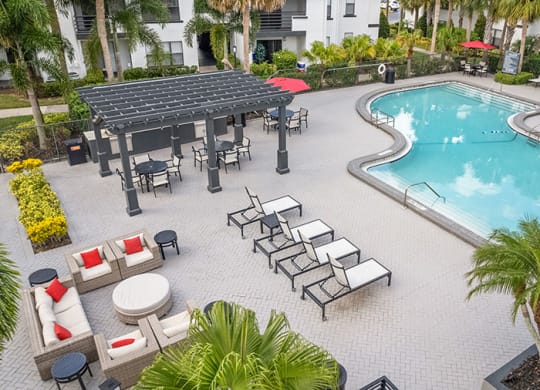 Aerial View of Community Swimming Pool and Pool Furniture at Rosehill Preserve Apartments in Orlando, FL.