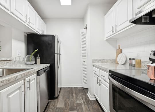 Model Kitchen with Wood-Style Flooring and White Cabinets at Rosehill Preserve Apartments located in Orlando, FL.
