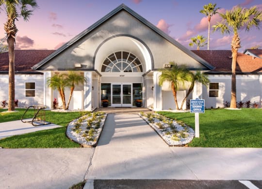 the front of a building with palm trees and a blue and white sign