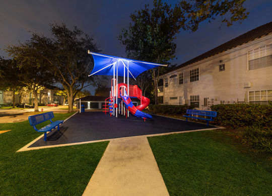 Community Playground with Slide and Blue Canopy at Vinings at Hunter's Green Apartments in Tampa, FL.