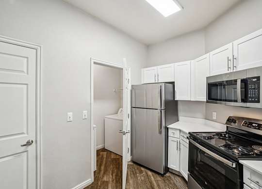 Model Kitchen with Wood-Style Flooring, White Cabinets, and Stainless-Steel Appliances at Altitude on Fifth Apartments located in Salt Lake City, UT.