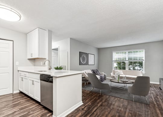 Model Kitchen with White Cabinets, Wood-Style Flooring and View of Living Room at Commons at Haynes Farm Apartments in Shrewsbury, MA.