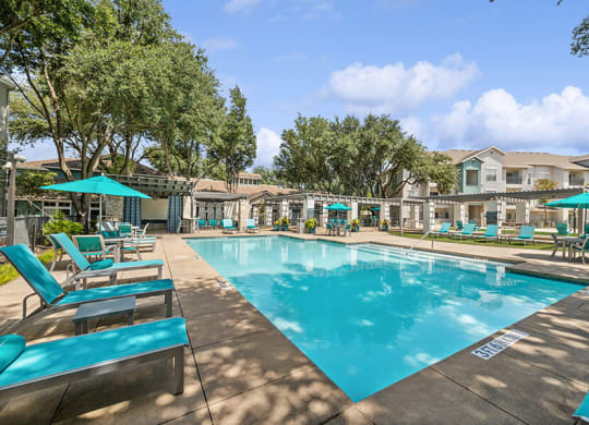 Community Swimming Pool with Pool Furniture at Essence Apartments in Dallas, TX.