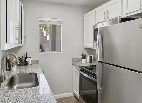 Model Kitchen with White Cabinets and Wood-Style Flooring at Hilands Apartments in Tucson, AZ.