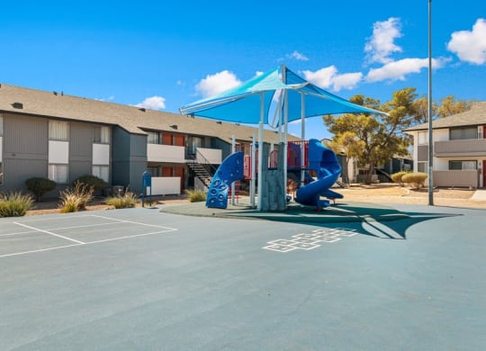 Pet-Friendly Apartments in West Las Vegas, NV - Accent on Rainbow - Courtyard Playground With Shade Canopy, Blue Slide, Painted Game Court, And Nearby Apartment Buildings