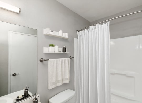 Model apartment bathroom with a shower curtain and a toilet and a sink