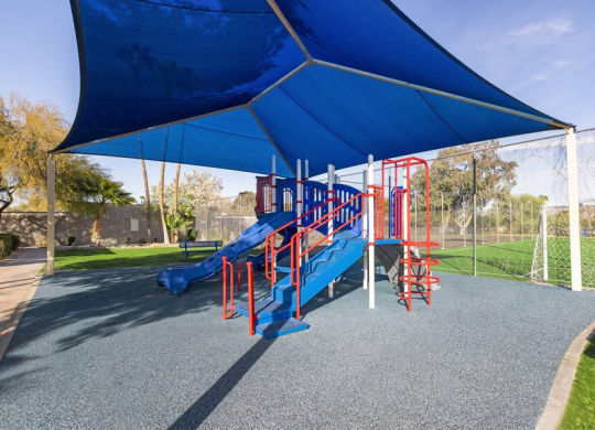 Community Playground with slide and blue canopy at Lakeside Casitas in Tucson, AZ.