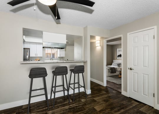 a kitchen with a breakfast bar and three stools in front of it at Villages at Metro Center, Phoenix, AZ