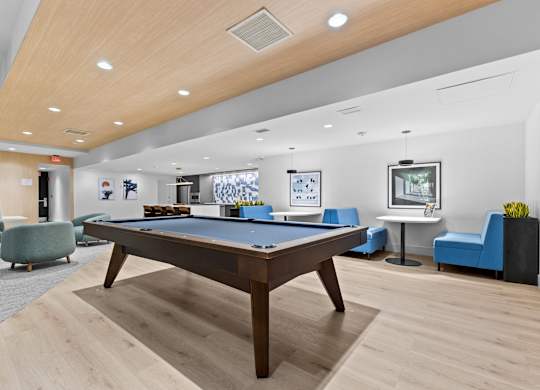 A room with a pool table and blue chairs.