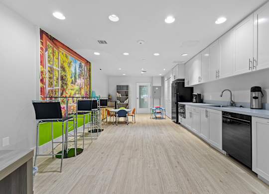 A modern kitchen with white cabinets and a wooden floor.