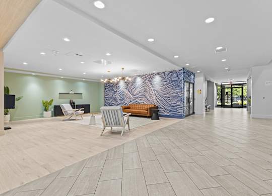 A spacious lobby with a blue and white abstract wall art, a wooden bench, and a blue sofa.