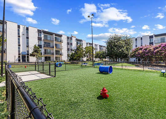 A red fire hydrant sits on a green lawn in a courtyard.