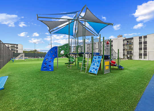 A playground with a blue slide and rockwalland a green slide.