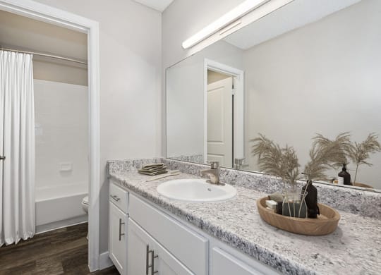 Model Bathroom with White Cabinets, Wood-Style Flooring and Shower/Tub at Peaks on 4th Apartments in Avondale, AZ.