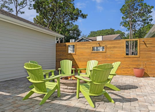 Fire pit with 4 green adirondack chairs on a brick patio at Retreat at Crosstown Apartments