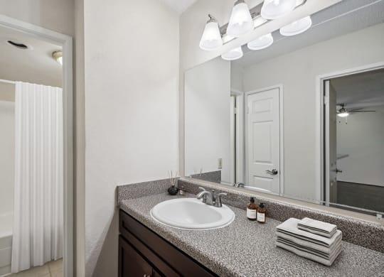 Model Bathroom with Dark Wood Cabinets, Tile Flooring & Shower/Tub at Mason Van Dorn Apartments located in Alexandria, VA.
