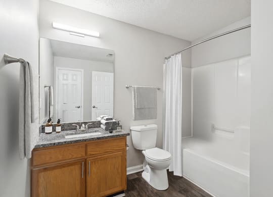 Model Bathroom with Wood-Style Flooring, Oak Cabinets and Shower/Tub at Retreat at Stonecrest Apartments located in Lithonia, GA.