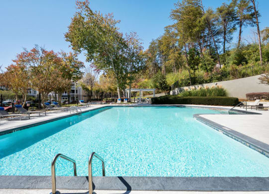One-Bedroom Apartments in Sandy Springs, GA - Edgewater at Sandy Springs - Resort-Style Swimming Pool With Wide Sundeck, Lounge Chairs, And Tree-Lined Views Under The Sky.