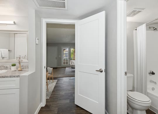 Model Master Bathroom with White Cabinets and Wood-Style Flooring at Stillwater Apartments in Glendale, AZ.