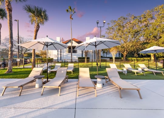 a group of lounge chairs with umbrellas in a park