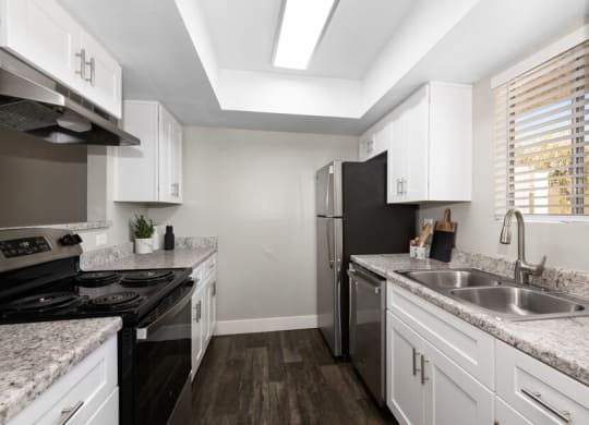 a kitchen with white cabinets and black appliances at Villages at Metro Center, Phoenix, Arizona