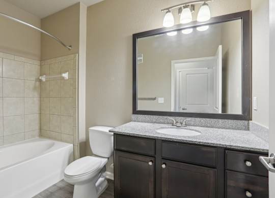 Model bathroom with a white toilet, sink, and bathtub.