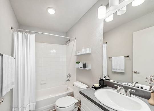Model Bathroom with White Cabinets, Wood-Style Flooring and Shower/Tub at Lake Cameron Apartments located in Apex, NC.