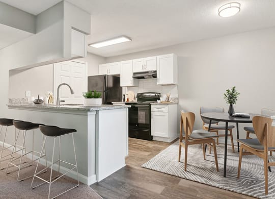 Model Dining Room and Kitchen with Wood-Style Flooring and White Cabinets at Park 2300 Apartments in Charlotte, NC.