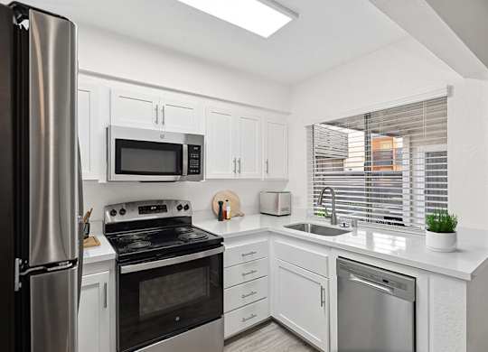 Model Kitchen with White Cabinets and Wood-Style Flooring at Horizon Apartments located in Santa Ana, CA.