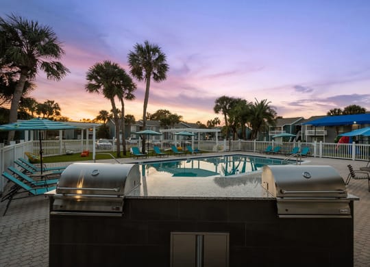 Outdoor BBQ Area with Furniture and Pool View at Park at 7200 Apartments in Jacksonville, FL.