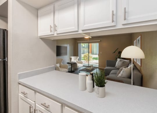 Model Kitchen with White Cabinets and Living Room View at Indigo Park Apartments in Albuquerque, NM.