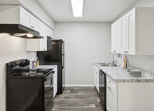 Model Kitchen with White Cabinets and Wood-Style Flooring at Tanque Verde Apartments located in Tucson, AZ.