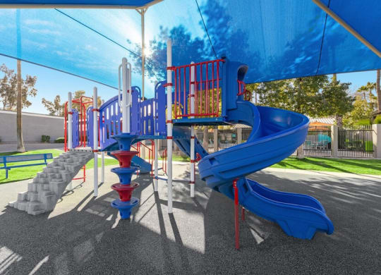 Community Playground with slide, rock wall climb, and blue canopy at Lakeside Casitas in Tucson, AZ.